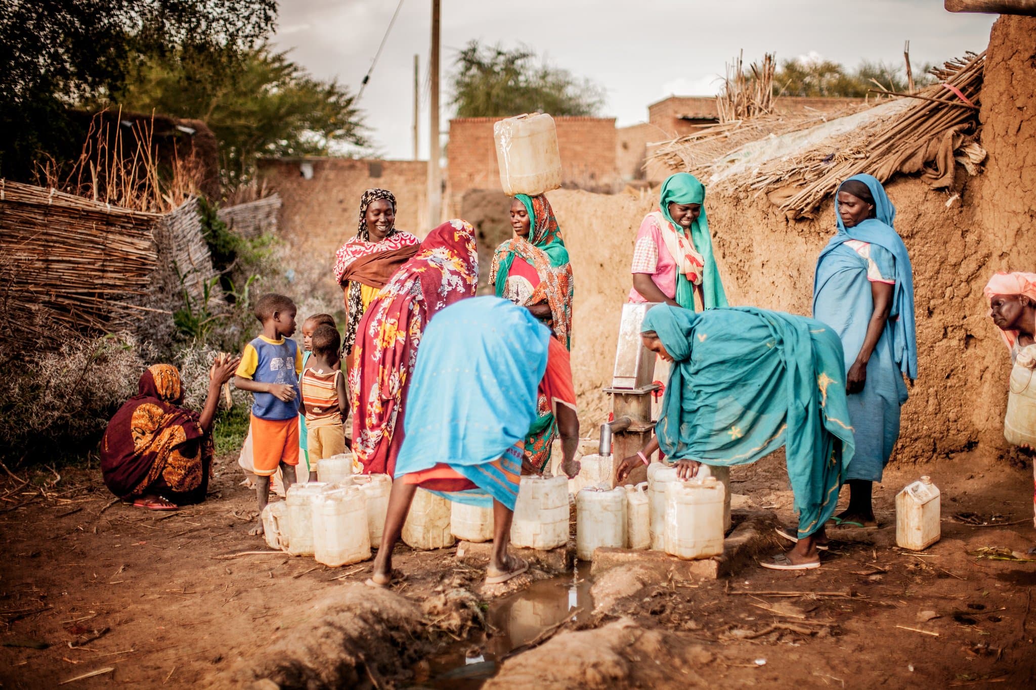 Women and children filling water containers at a well