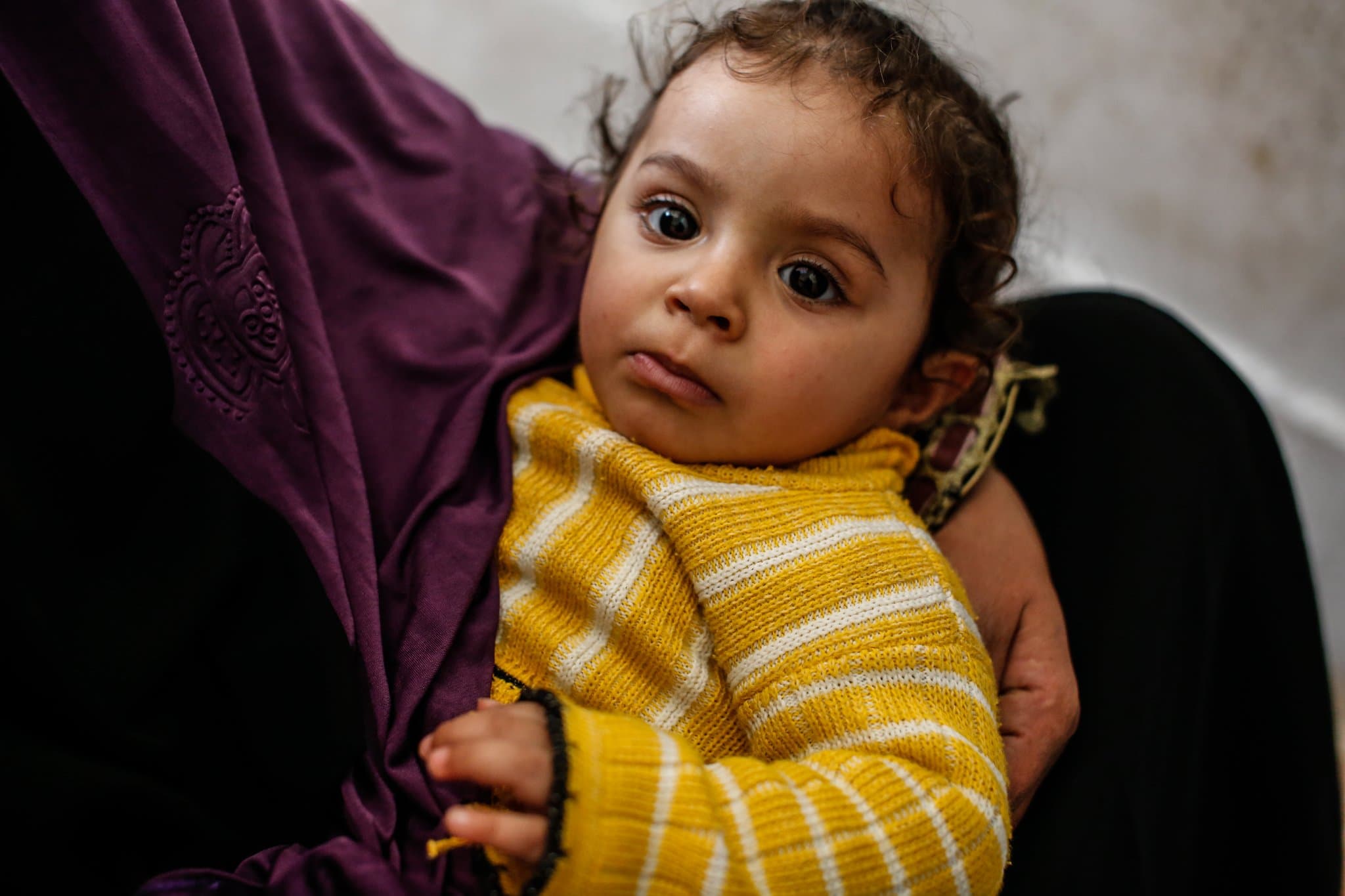 A young child held by her mother