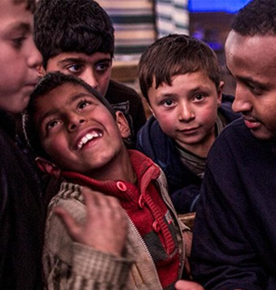 Smiling children with a Muntada Aid team member