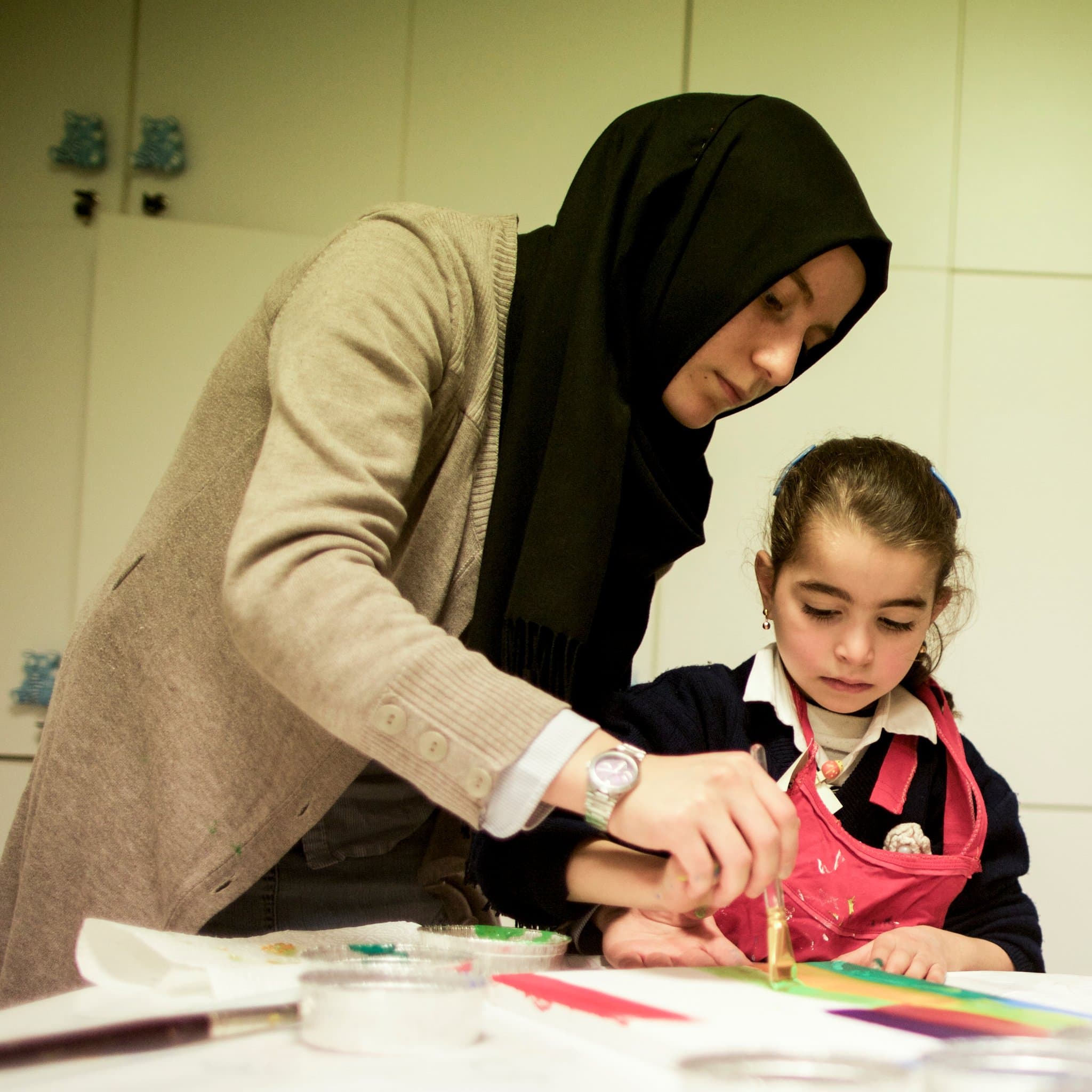 A teacher helping a girl paint