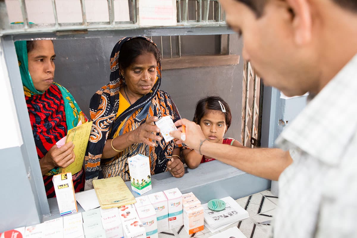 A pharmacist handing medicine to a mother and her daughters